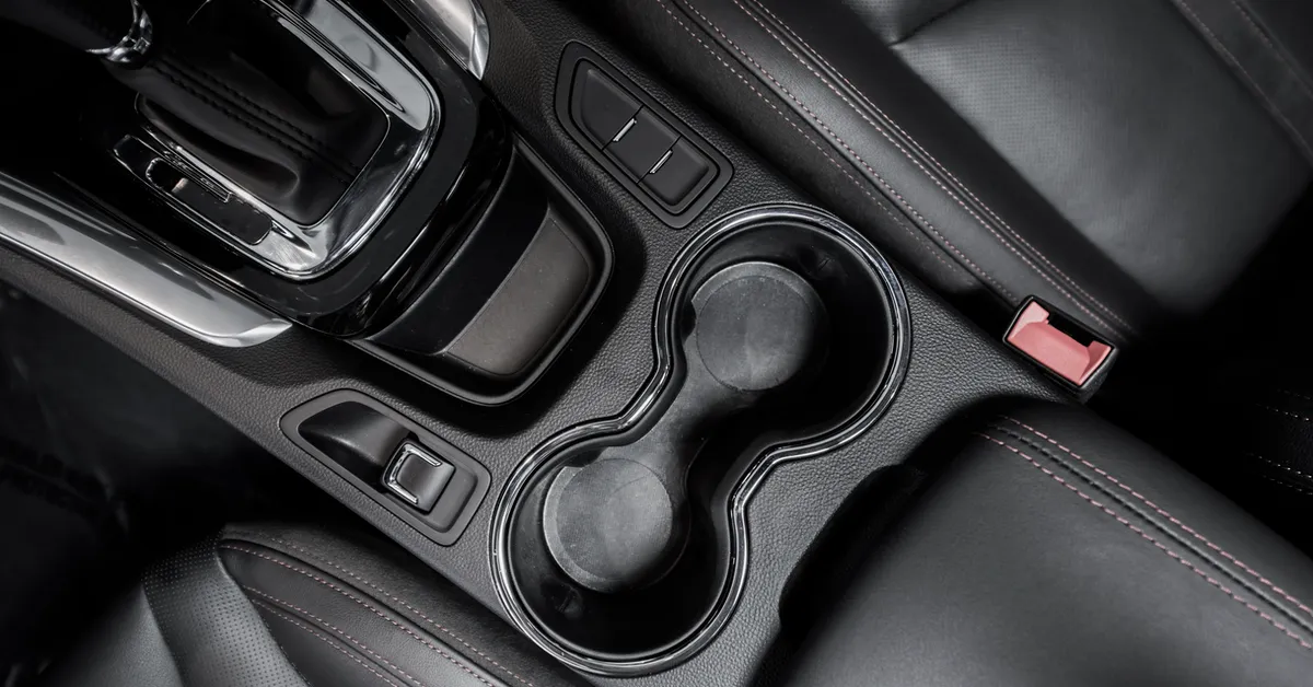 A black car interior with a gear shift and cup holders.